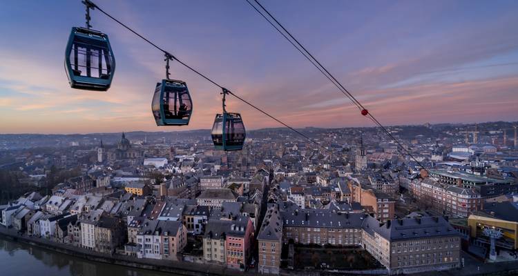 Cable cars over a cityscape at sunset.