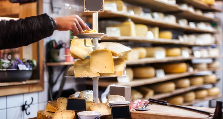Person selecting cheese in a cheese shop.