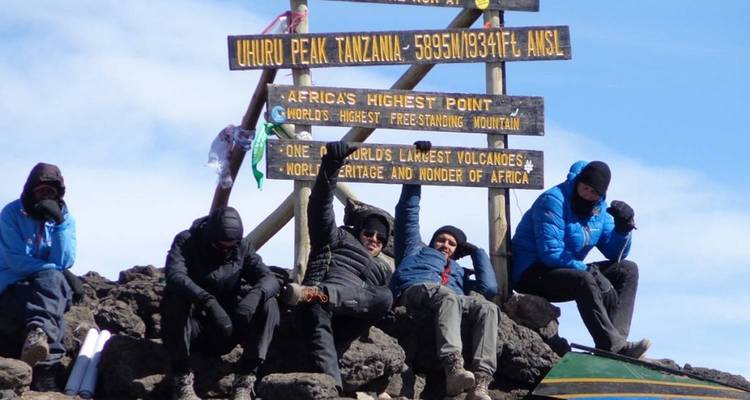 Wanderer feiern am Uhuru Peak Schild auf dem Kilimandscharo.