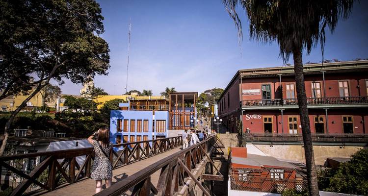 Visitors cross the wooden Bridge of Sighs in Lima’s bohemian Barranco district lined with colorful buildings.