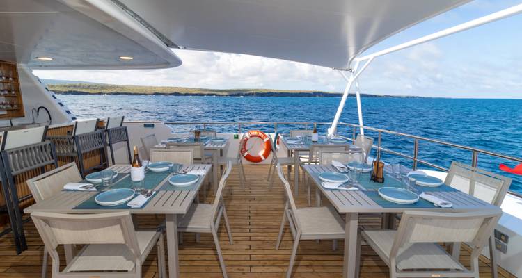 Outdoor dining area on a boat overlooking the sea.