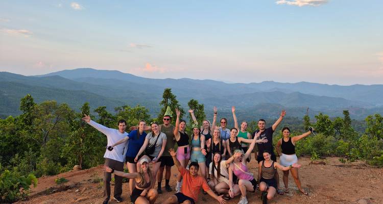 Een groep mensen die vrolijk poseren op een bergkam tijdens zonsondergang.