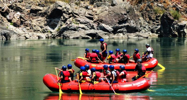 Groep mensen die raften op een rustige rivier omringd door rotsachtig terrein.