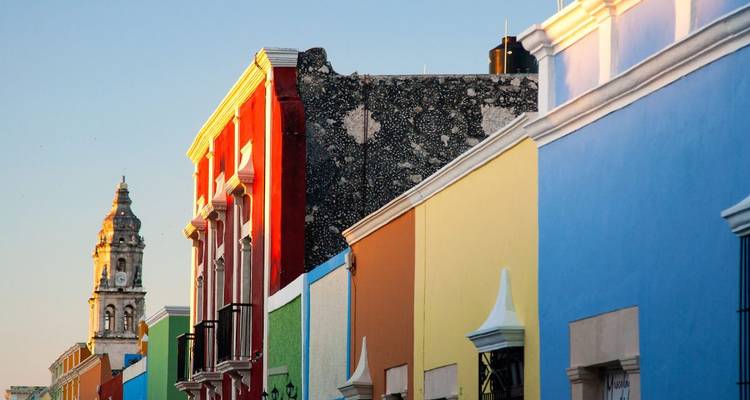 Colorful colonial buildings lining a street with a church tower in the background.