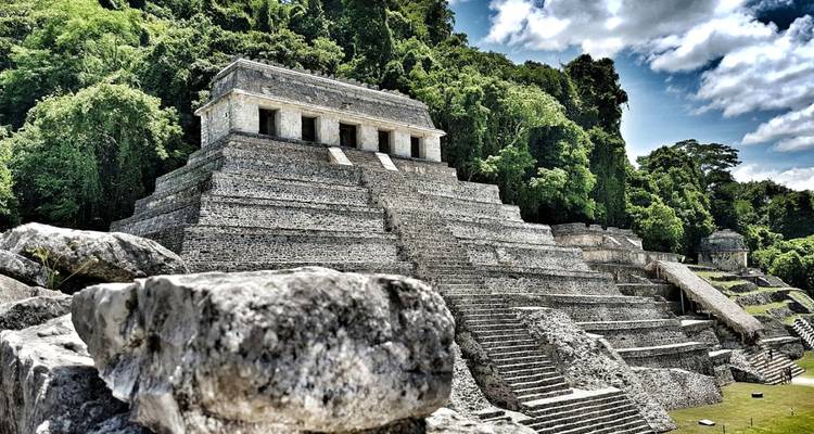 Ancient Mayan ruins in a lush jungle setting with stone steps leading to a temple.