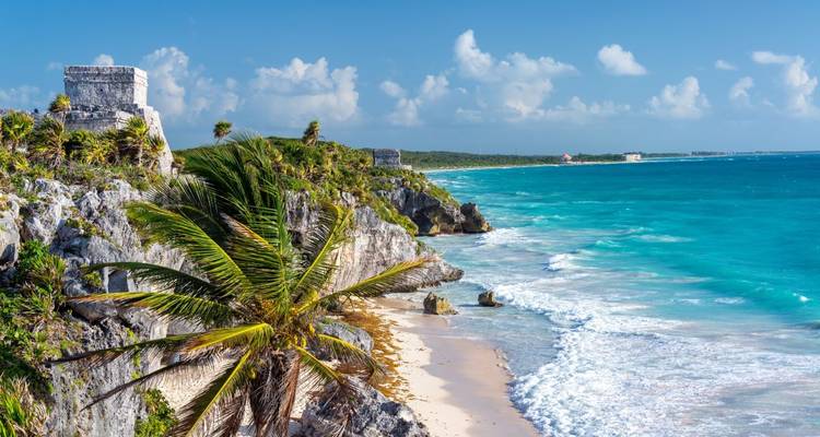 Coastal view with Mayan ruins overlooking a turquoise sea.