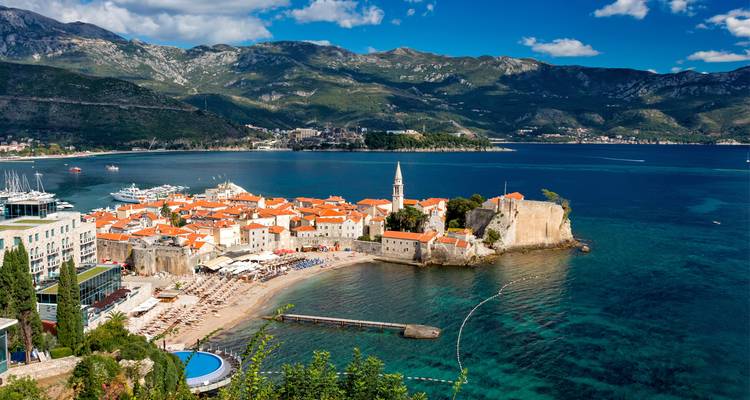 Vue panoramique sur la vieille ville de terre cuite de Budva, la plage de sable et l'Adriatique encadrée par les montagnes