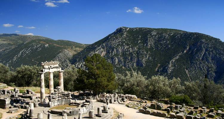 Weiter Blick auf das antike Heiligtum von Delphi mit Bergkulisse und Olivenhainen.