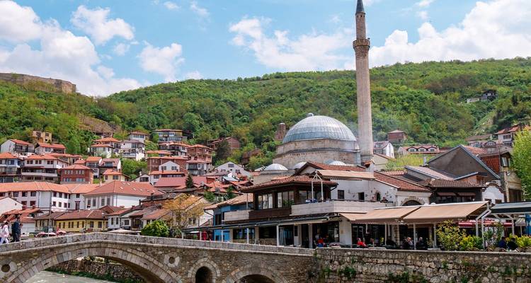 Die Steinbrücke und die Moschee mit Kuppel erheben sich über die farbenfrohen Häuser am Hang von Prizren.