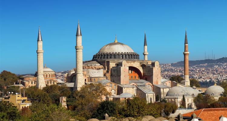 Buitenaanzicht van de Hagia Sophia met minaretten en een heldere blauwe lucht.