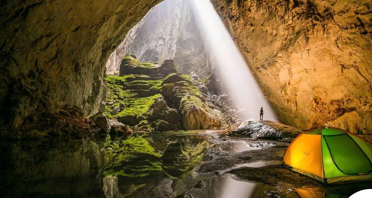 Une vaste grotte avec une cascade et un terrain de camping.