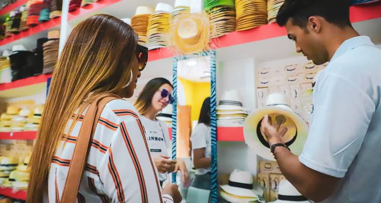 Los viajeros se prueban sombreros Panamá con la ayuda de un amable guía local.