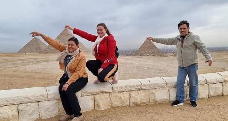 People posing playfully with pyramids in the background.