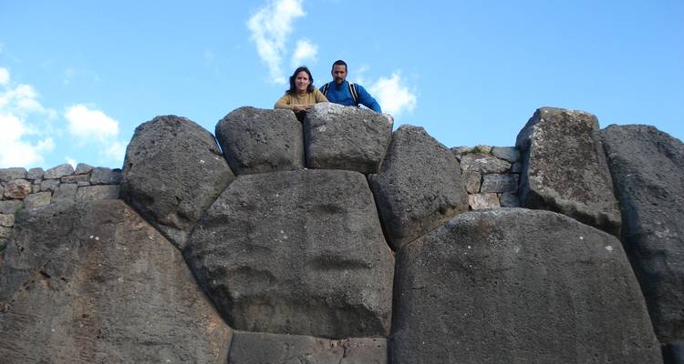 Deux voyageurs regardant par-dessus les imposants murs de pierre de la forteresse inca de Sacsayhuamán.