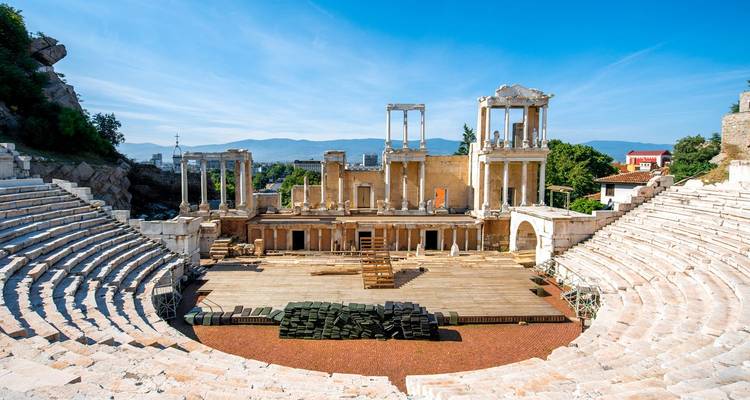 Ancient Roman amphitheatre in Plovdiv with stone seating and restored stage overlooking the city and mountains