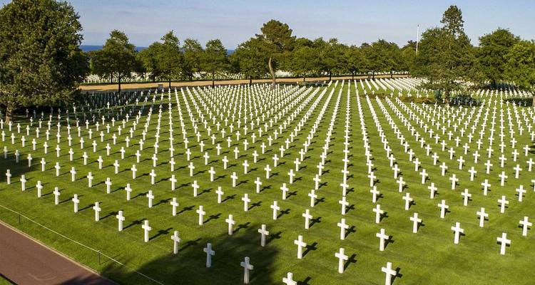 Des rangées infinies de croix blanches marquent un vaste cimetière militaire aux pelouses impeccablement entretenues.