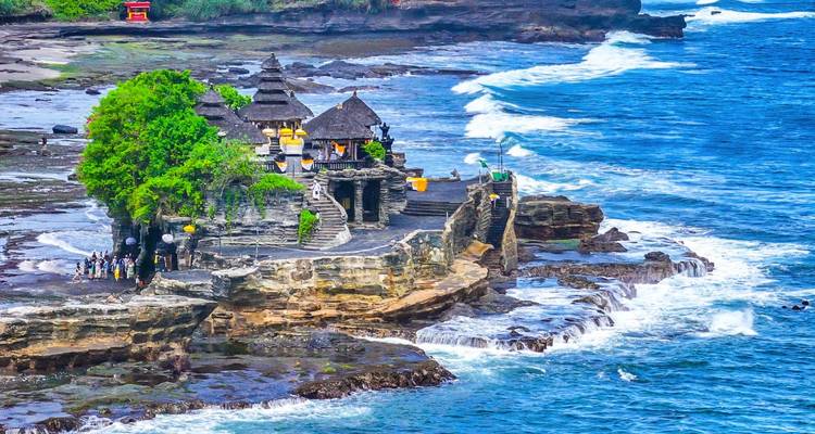 Le temple de mer de Tanah Lot perché sur un promontoire rocheux parmi les vagues turquoise déferlantes.