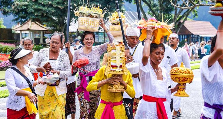 Les villageois balinais vêtus de costumes traditionnels colorés portent des offrandes ornées lors d'une procession animée dans les rues.