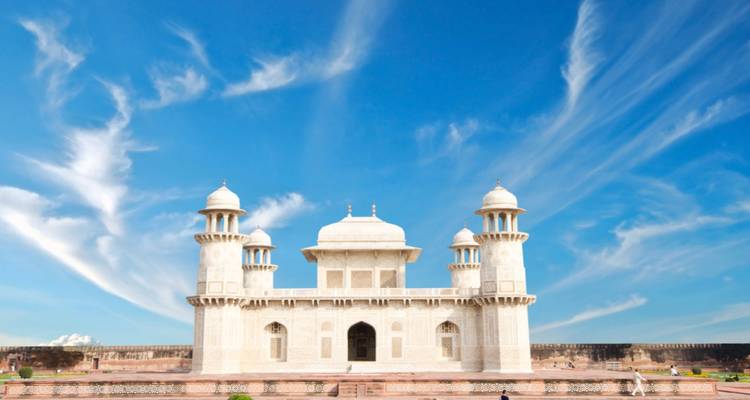 Een wit marmeren graf tegen een heldere lucht met wervelende wolken.