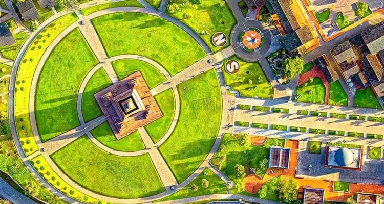 Kleurrijke luchtfoto van het Mitad del Mundo park met cirkelvormige wandelpaden en centraal monument.
