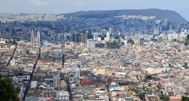 Breed panoramisch uitzicht over de uitgestrekte skyline van Quito, gezien vanaf een heuvelpunt.