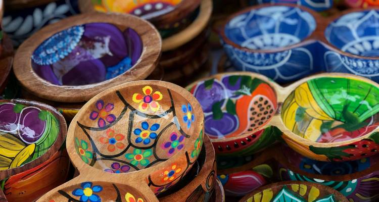 Des bols en bois peints à la main, aux couleurs vives, exposés à un étal du marché.