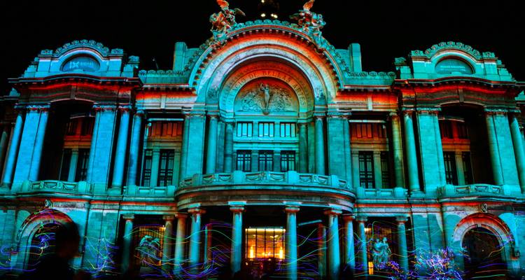 Palacio de Bellas Artes illuminé de projections bleu vif et rouge lors d'un spectacle lumineux nocturne.