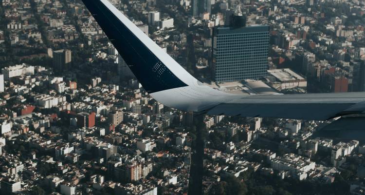 Aile d'avion en vol au-dessus de l'expansion urbaine dense de Mexico.