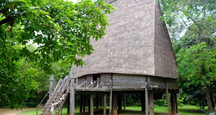 Traditioneel paalwoning omgeven door bomen.
