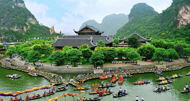 Boats filled with tourists in a scenic area with traditional architecture.