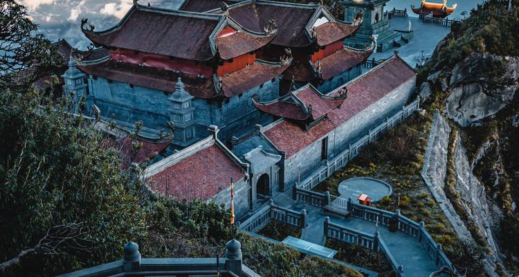 Vista aérea de un templo con arquitectura ornamentada y techos rojos en una ladera.