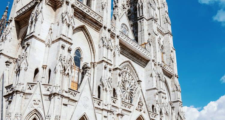 Fachada de piedra blanca brillante de la Basílica del Voto Nacional contra un cielo azul profundo.