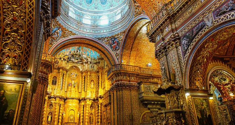 El interior dorado y opulento de la iglesia La Compañía de Jesús brilla bajo una iluminación suave.