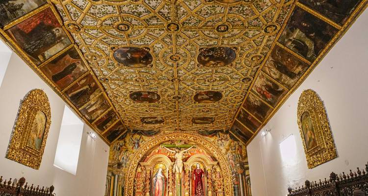 Techo y altar de madera intricadamente pintados y dorados de una iglesia histórica de Quito.