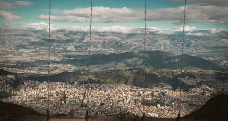 Ciudad de Quito vista a través de tres cadenas de columpio colgantes desde un popular punto de vista en una colina.