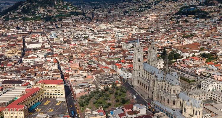 Vista elevada del denso distrito histórico de Quito con la Basílica y la colina El Panecillo más allá.
