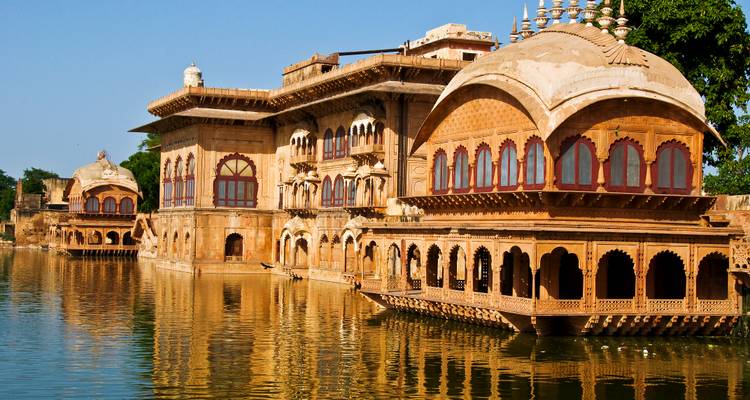 Een prachtig sierlijk gebouw met bogen weerspiegeld in het water.