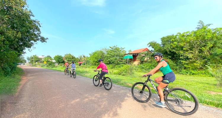 Cyclisme en petit groupe sur une route rurale pavée tranquille, bordée de verdure luxuriante