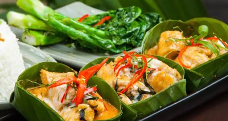 Curry cambodgien traditionnel servi dans des coupes en feuilles de bananier avec du riz et des légumes