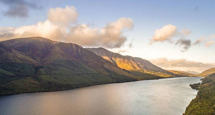 Panoramic view of a loch surrounded by mountains.