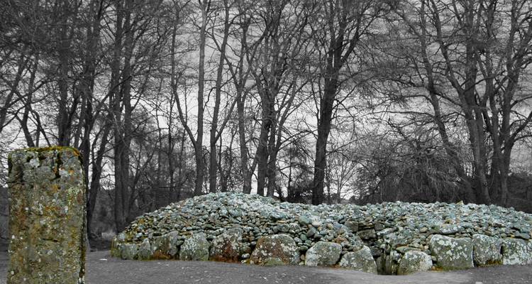 Cairn de pierres dans une forêt aux arbres dénudés.