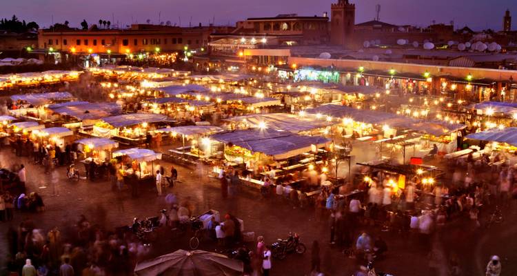 Place animée du marché nocturne illuminée par des centaines d'étals de restauration et des foules floues à Marrakech