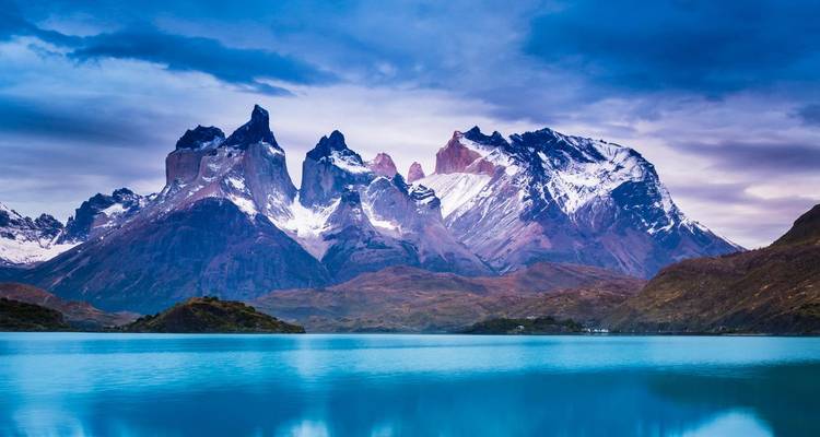 Picos nevados espectaculares de Torres del Paine reflejados en un lago glacial de color turquesa.