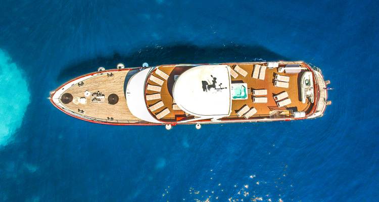 Vista aérea de un yate en aguas azules.