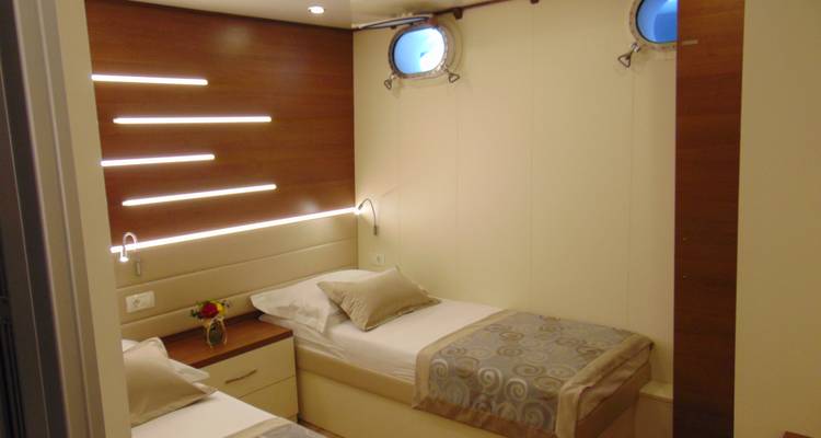 Interior de camarote con dos camas individuales y ojos de buey.