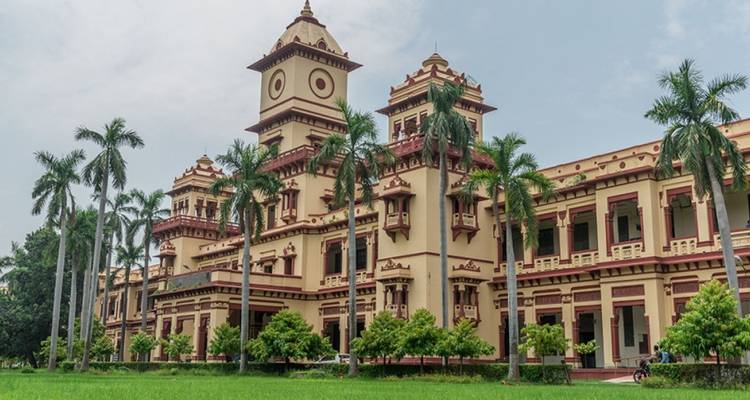 Bâtiment de style colonial avec palmiers et pelouse verte.