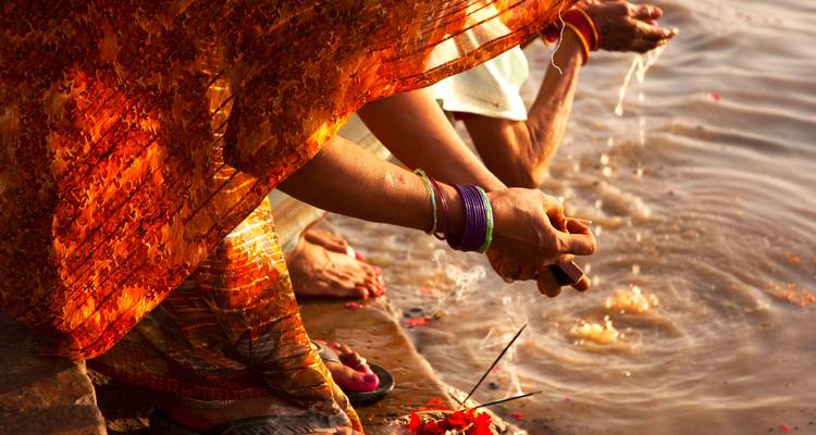 Gros plan d'une femme effectuant un rituel au bord d'une rivière.