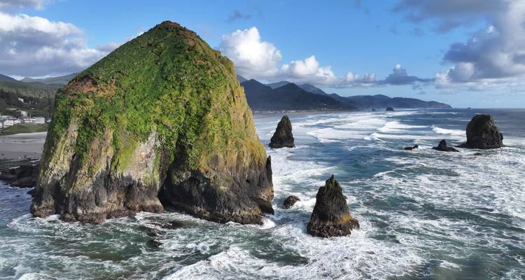 Ocean waves crashing against large rocky formations.