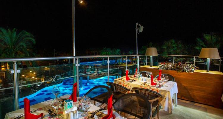 Außenbereich zum Speisen mit Poolblick bei Nacht.