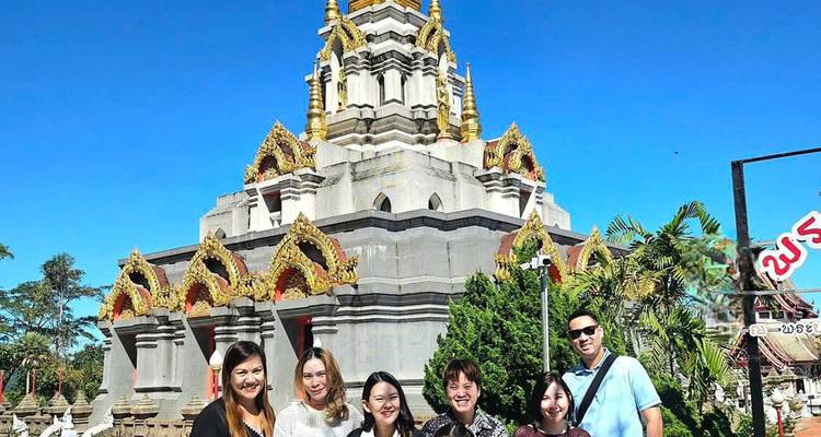 A group of people posing in front of a temple with intricate details.